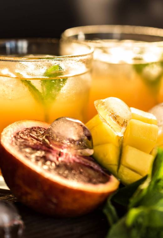 Jars with various cold-pressed raw tropical fruit juice or smoothie. Pineapple, mango and orange mix. Refreshments and summer drinks or cocktails concept. Selective focus